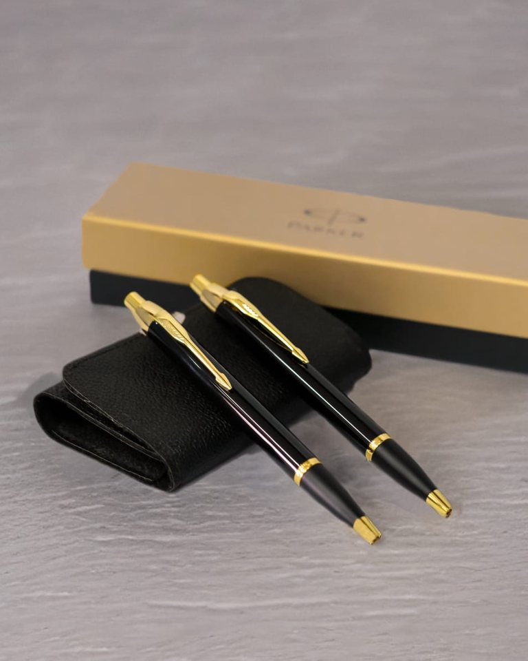 Jasa fotografi produk makanan dengan dua pulpen hitam dan emas di atas tas kulit hitam.