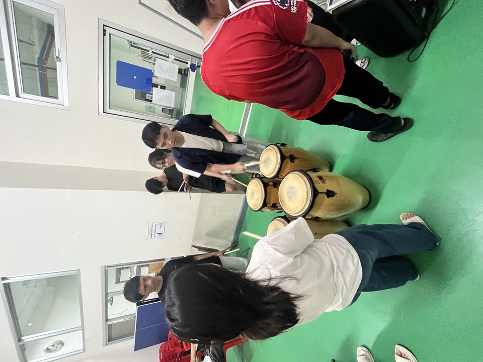 เรียนดนตรี กับกลุ่มนักเรียนดนตรี ในชั้นเรียนดนตรี โดยมีครูสอนดนตรี ช่วยสอนดนตรี บนเวที มีเครื่องดนตรี เรียนรู้การเล่นดนตรี