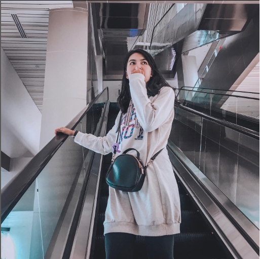 Jasa Fotografi Profesional Wanita Berpose di Eskalator dengan Tas Kamera di Tangan