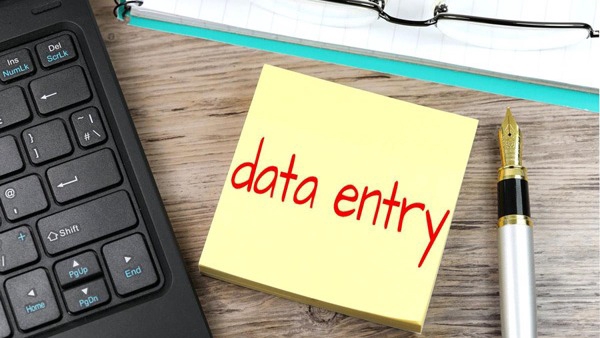 Jasa input data online dengan keyboard dan pulpen di atas meja kayu