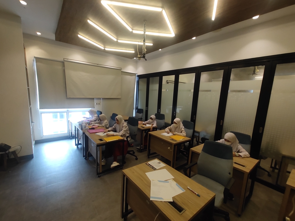 Ruangan kelas online dengan siswa yang sedang belajar dengan guru di depan papan tulis.