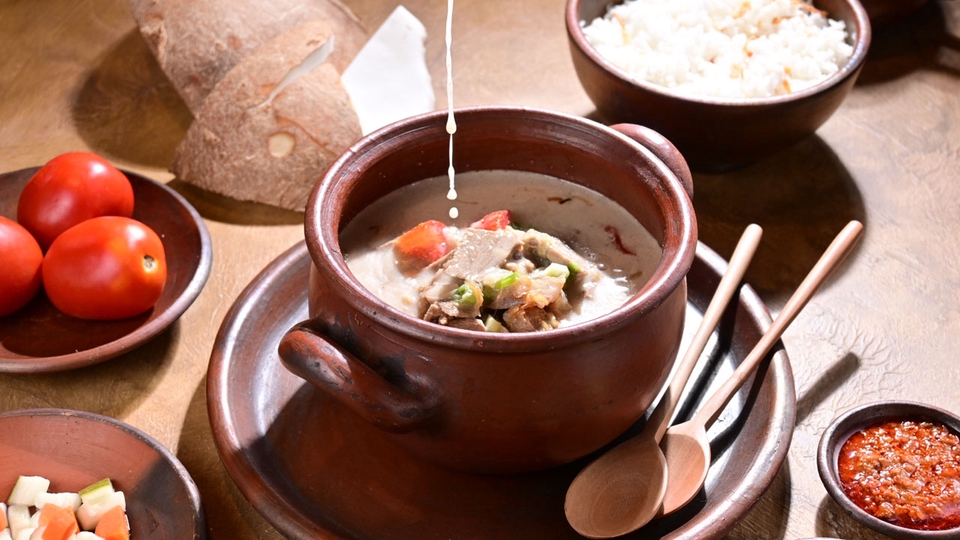 Jasa fotografi makanan dengan konsep tradisional Indonesia, menampilkan makanan soto dengan kuah santan dan daging di mangkuk tanah liat