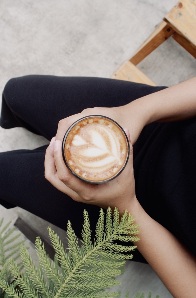 Jasa Fotografi Makanan: Foto tangan memegang segelas kopi dengan latte art.