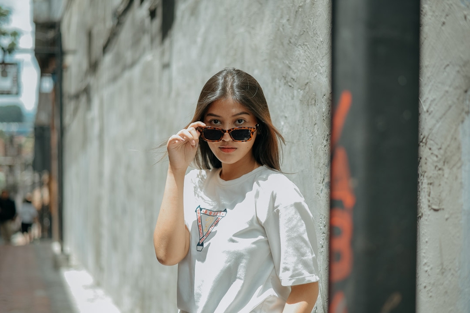 Jasa Fotografi Produk Online Shop - Wanita cantik memakai kacamata hitam sedang berpose dengan latar belakang putih.