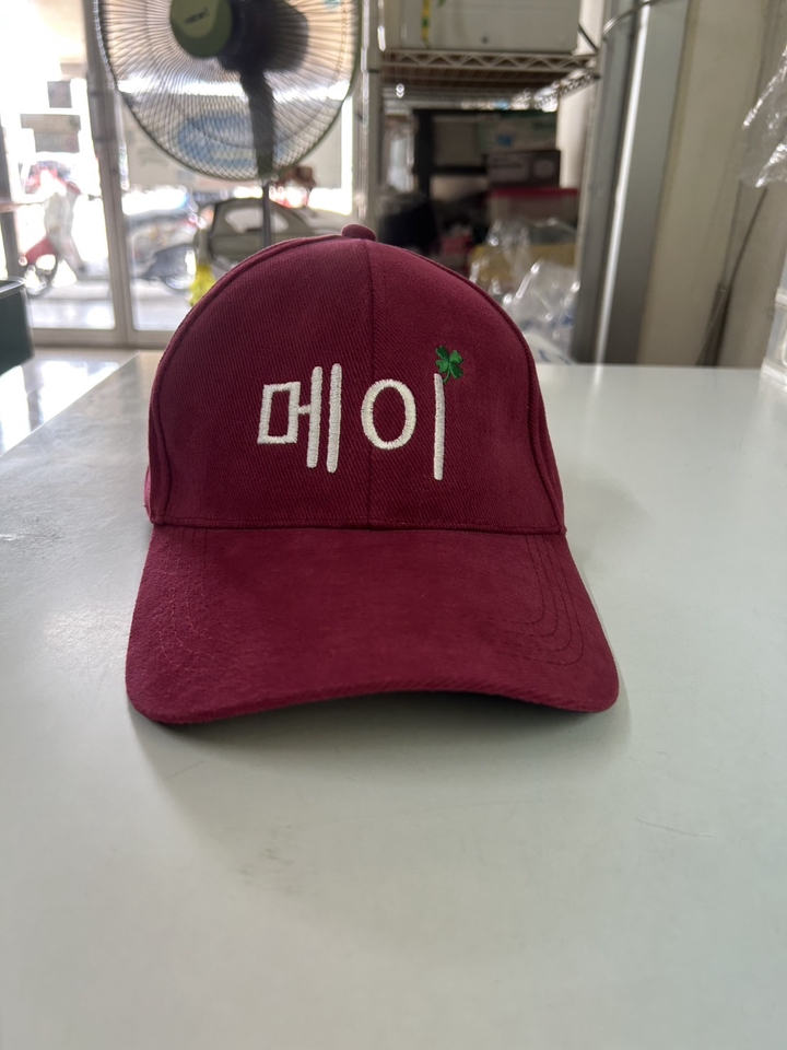 รับสกรีนเสื้อ หมวกแก๊ป สีแดง มีตัวอักษรเขียนว่า "เมย"