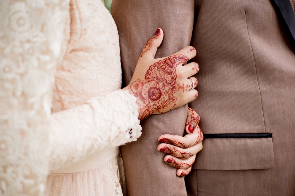 Jasa Fotografi Prewedding - Pasangan pengantin baru berpegangan tangan dengan tangan wanita yang dihiasi henna.