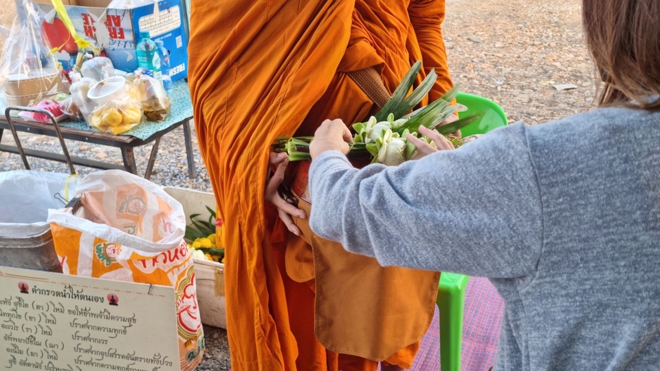 รับจ้างทำบุญออนไลน์ บุคคลกำลังทำบุญโดยการใส่บาตรพระสงฆ์