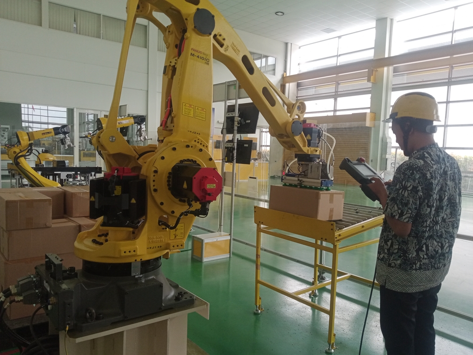 Jasa Pembuatan Robot Arduino - Robot lengan kuning sedang melakukan pekerjaan di area gudang.