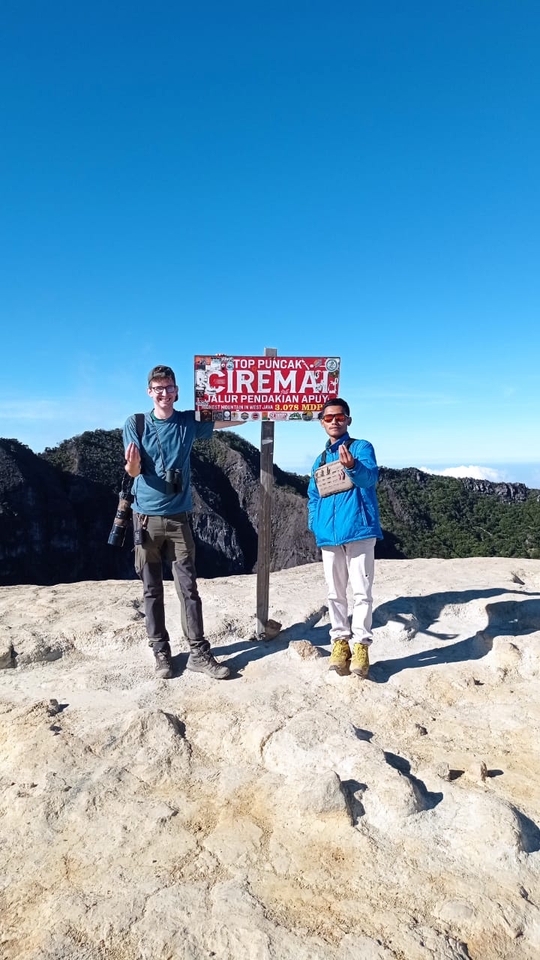 Dua pelancong berdiri di puncak Gunung Ciremai, Jawa Barat, menikmati pemandangan alam yang menakjubkan.