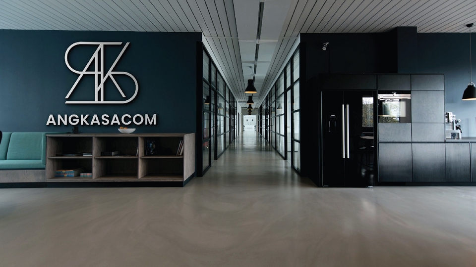 Desain logo perusahaan minimalis dengan latar belakang ruangan kantor modern.