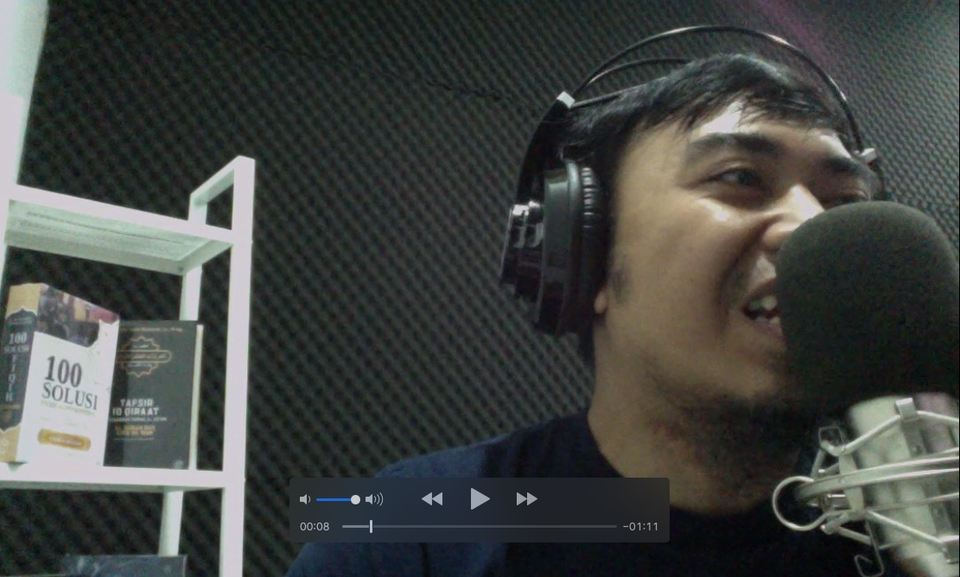 Pengisi suara pria profesional dengan headphone sedang mengerjakan proyek voice over