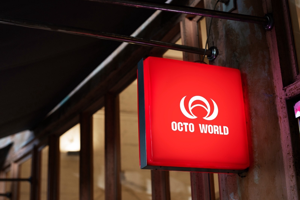 Desain logo merah dengan tulisan Octo World di dalam kotak hitam