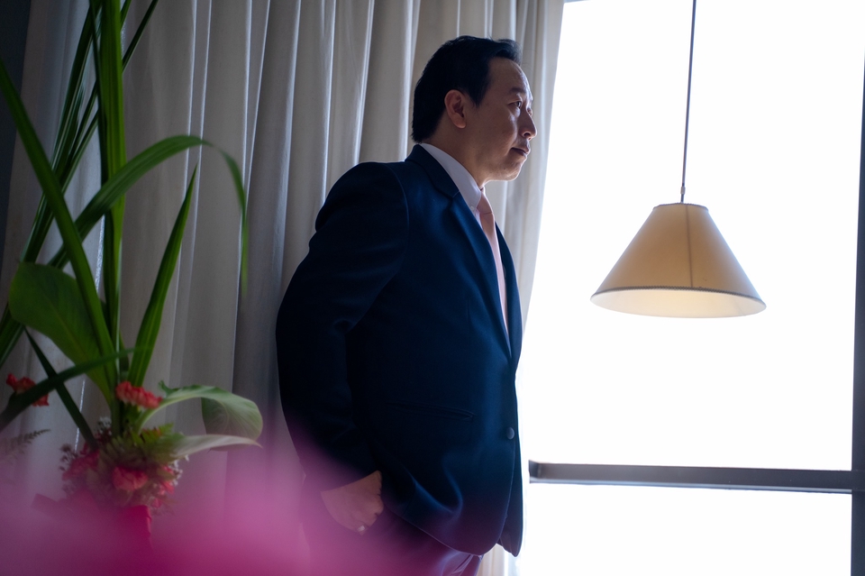 ช่างภาพชายสวมสูท ยืนอยู่หน้าต่าง ในการถ่ายภาพบุคคล