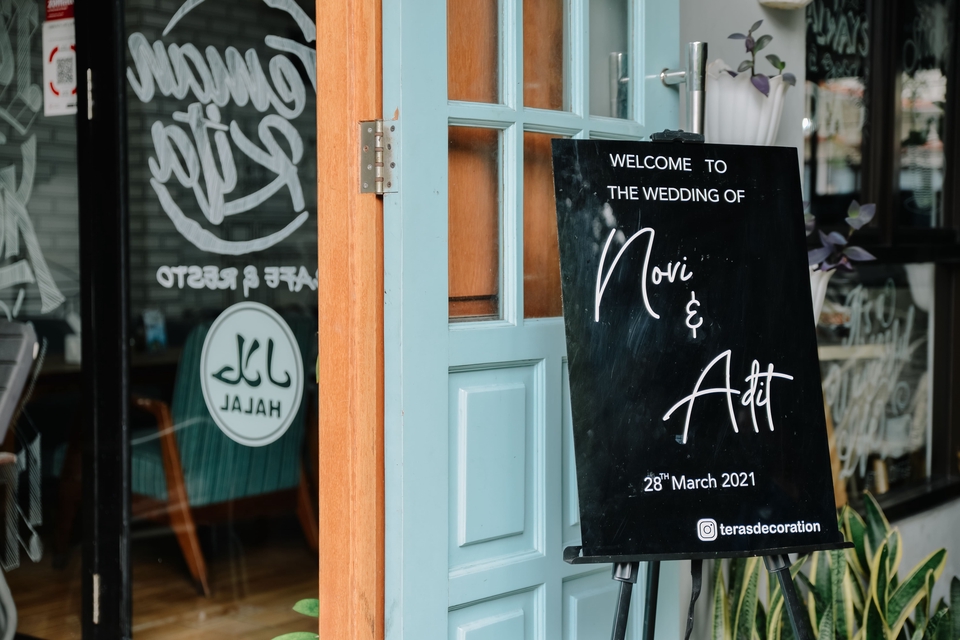 Jasa Fotografi Pernikahan Novi & Adit dengan tema pernikahan simple dan elegan di dekorasi teras dengan background pintu kayu