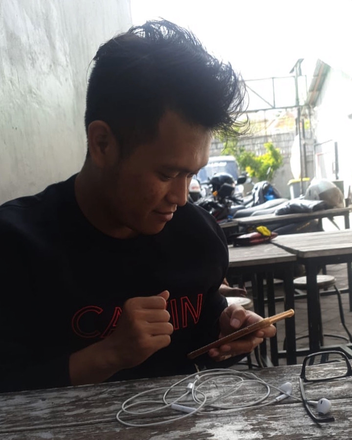 Man in black shirt with red writing using smartphone for online self development services