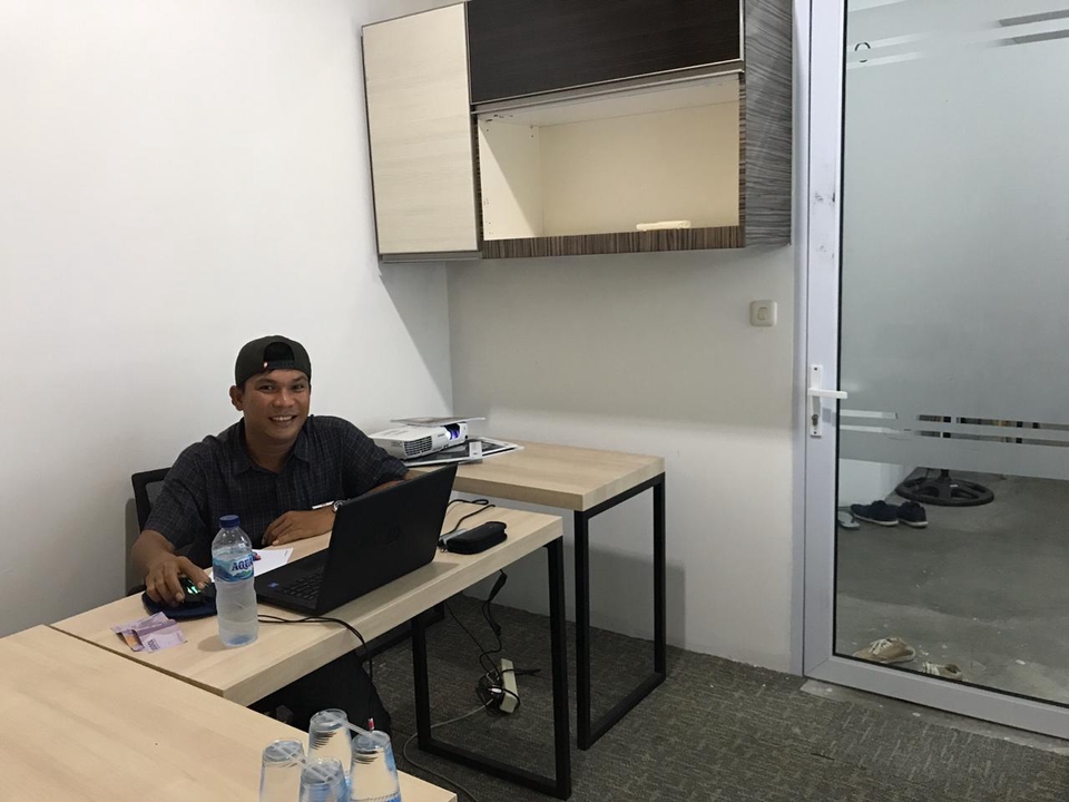 Seorang freelancer pria muda sedang belajar bahasa Inggris di depan laptop di kantornya.