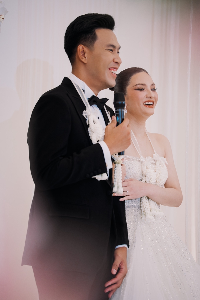 คู่บ่าวสาวกำลังพูดบนเวทีงานแต่งงาน โดยมีช่างภาพถ่ายวีดีโอ