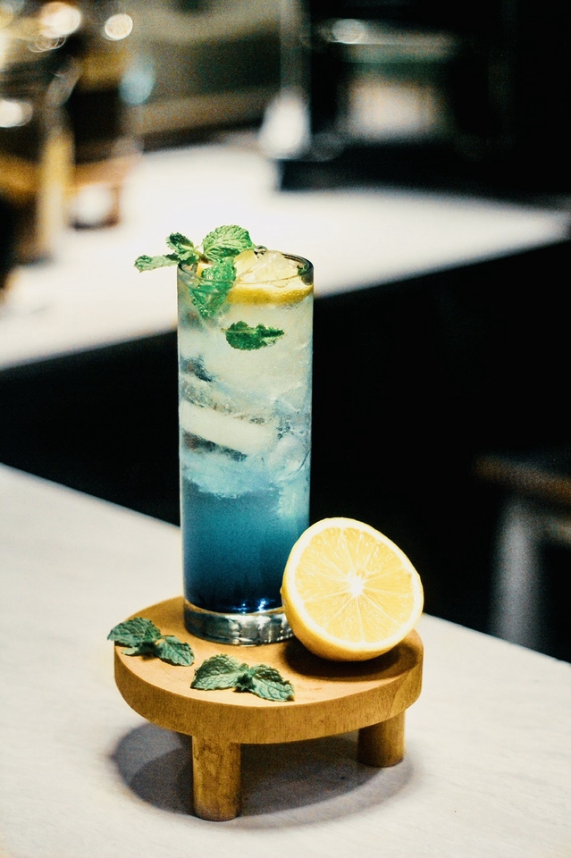 Jasa fotografi makanan dengan minuman biru dan jeruk lemon di atas alas kayu