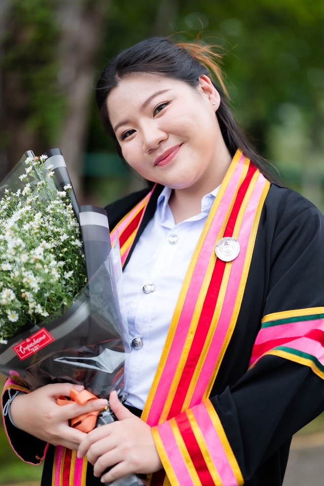 ช่างภาพ รับถ่ายรูปรับปริญญา กรุงเทพฯ บริการถ่ายภาพรับปริญญา บัณฑิตหญิงสวย ใบหน้ายิ้มแย้ม ถือช่อดอกไม้