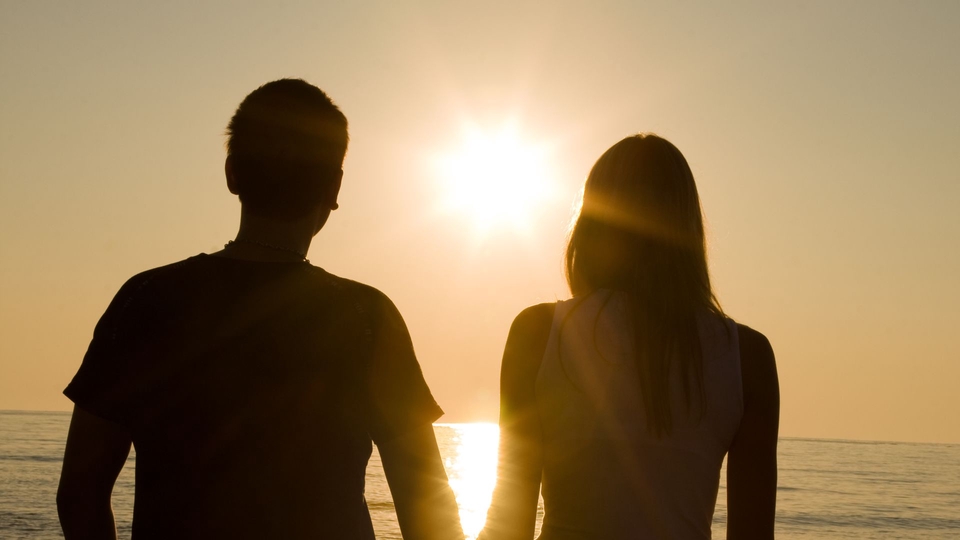 Siluet pria dan wanita di tepi pantai, menggambarkan perjalanan penemuan diri dan pengembangan diri.