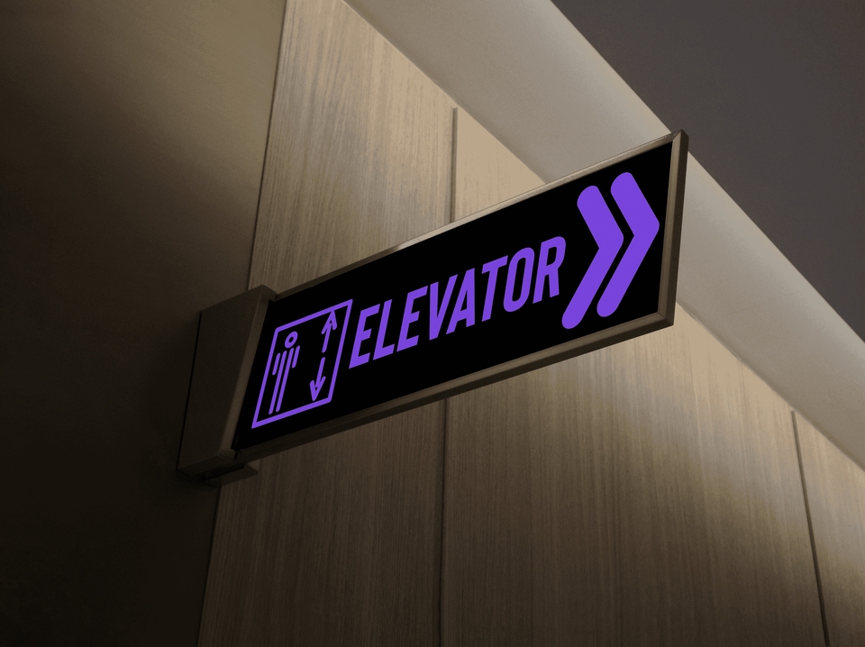 Tanda pintu lift dengan tulisan "Elevator" dan simbol panah ke atas di sebuah gedung