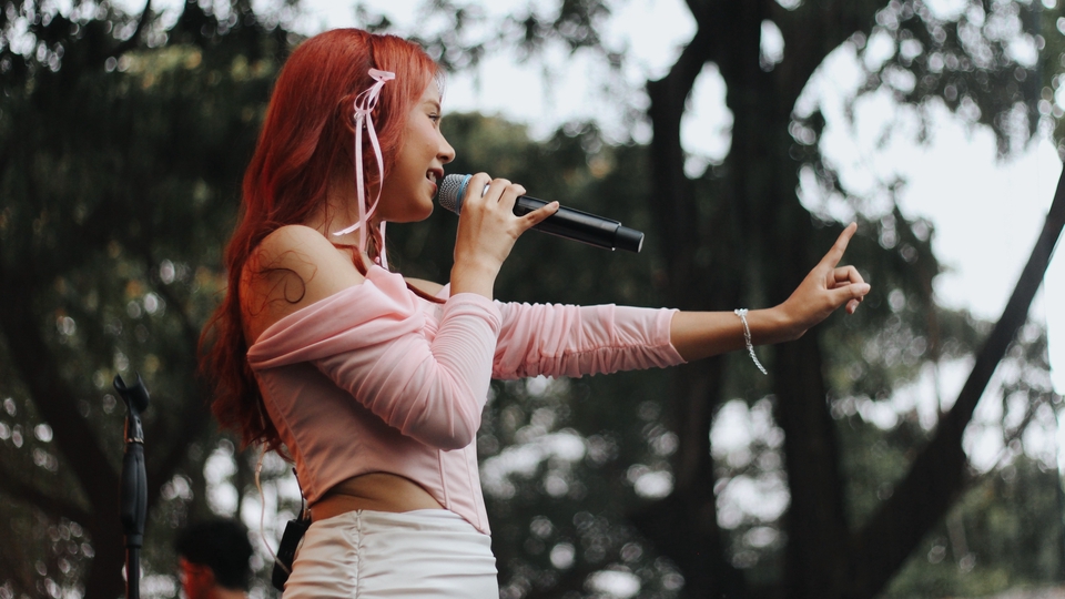 Jasa fotografi wanita profesional bernyanyi dengan mikrofon di luar ruangan