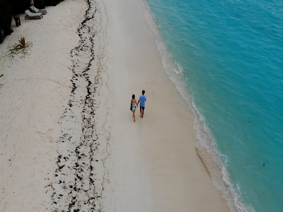 คู่รักเดินบนชายหาดสีขาว ใกล้กับน้ำทะเลสีฟ้า รับถ่ายวีดีโองานแต่งงาน รับถ่ายวีดีโอ