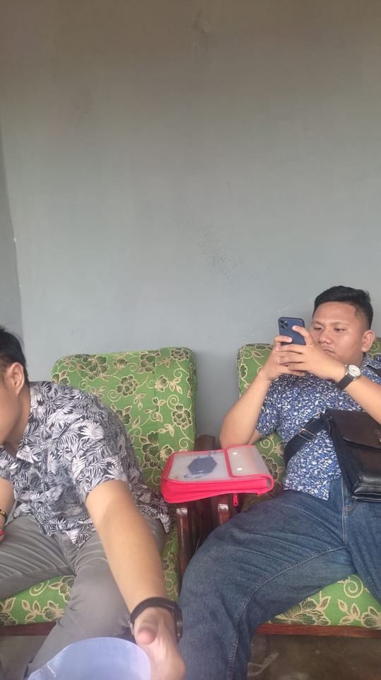 Dua orang pria sedang duduk di sofa dengan seorang pengacara konsultan legal freelance sedang melihat telepon seluler dan satunya sedang melihat dokumen hukum.