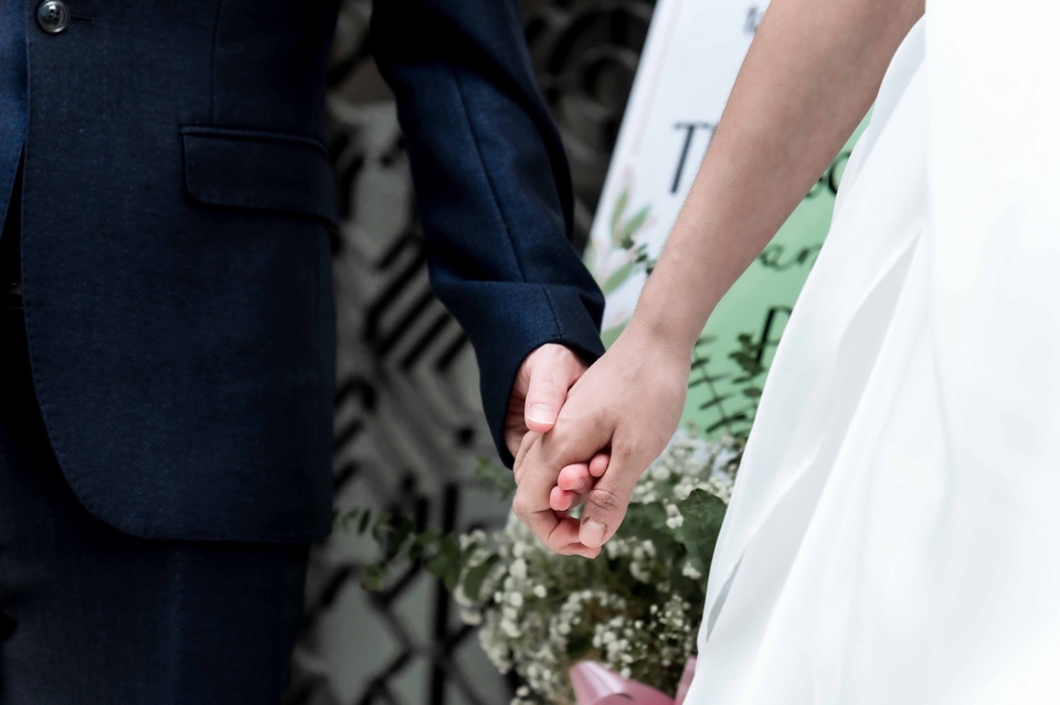 คู่บ่าวสาวจับมือกันอย่างมีความสุข ในงานแต่งงาน โดยมีช่างภาพวีดีโอถ่ายภาพ