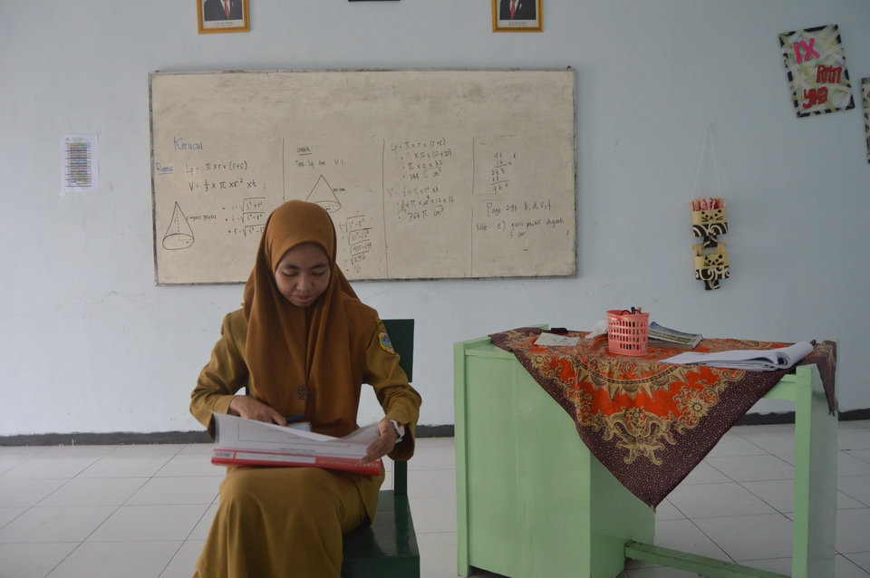 Siswa wanita muda belajar di kelas dengan buku dan laptop di meja. Kursus online bahasa Inggris.