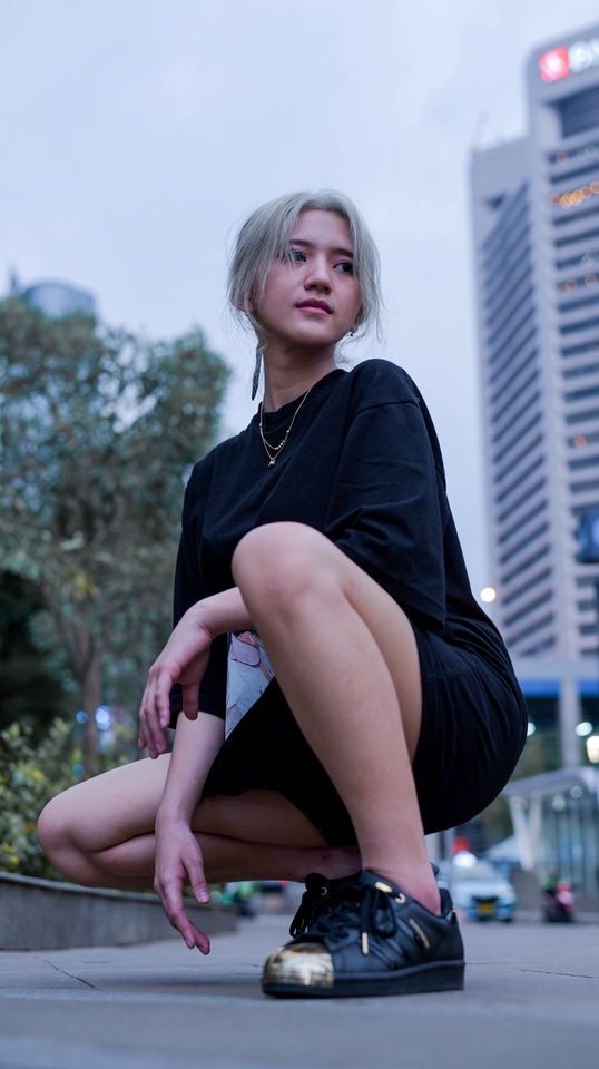 Jasa fotografi freelance, fotografer wanita berpose di depan gedung bertingkat, harga jasa fotografer freelance