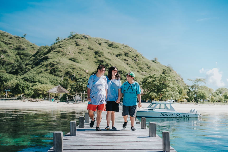 Jasa fotografi keluarga di pantai dengan latar belakang pemandangan gunung dan perahu