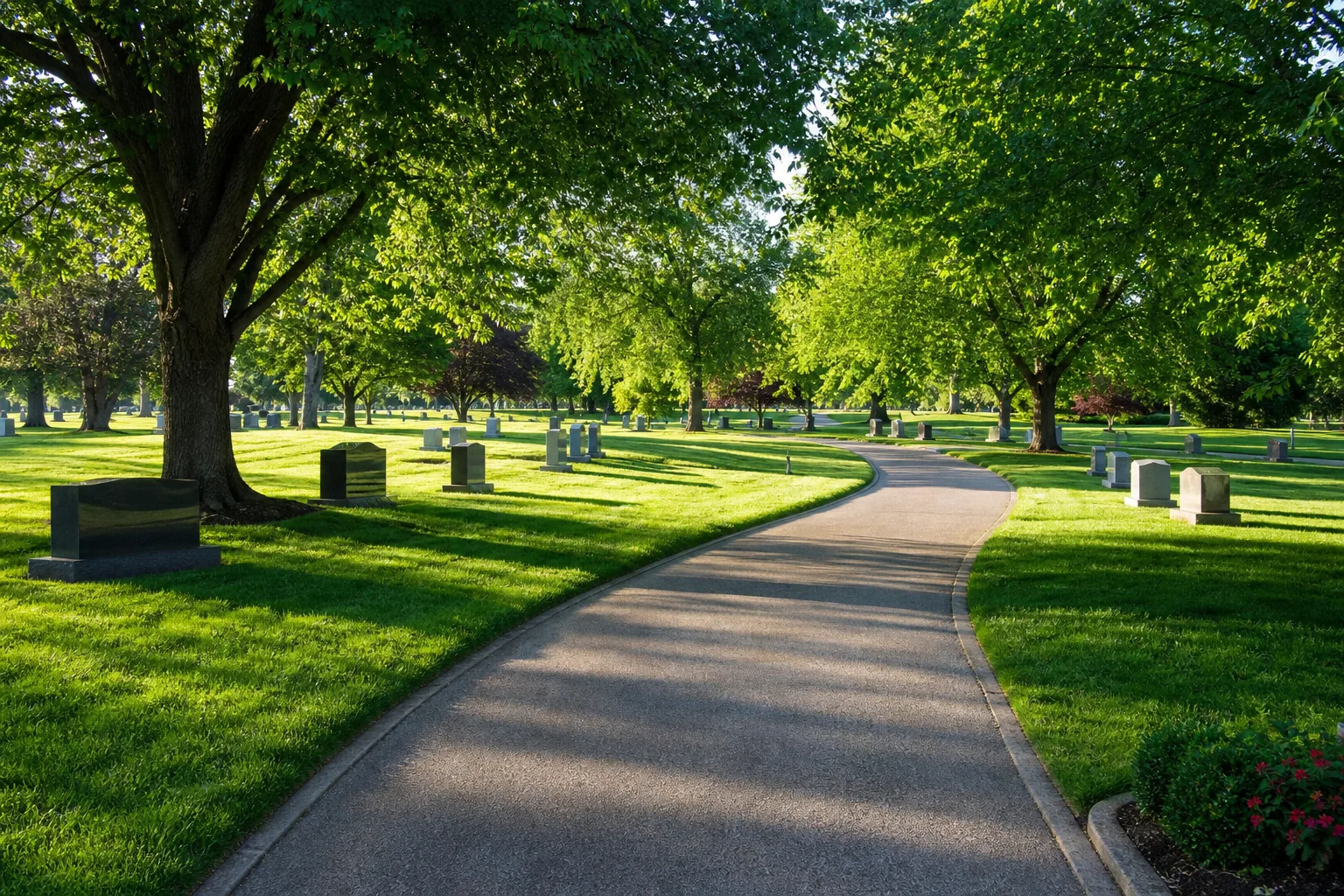 A paved path through a well-kept park-style cemetery