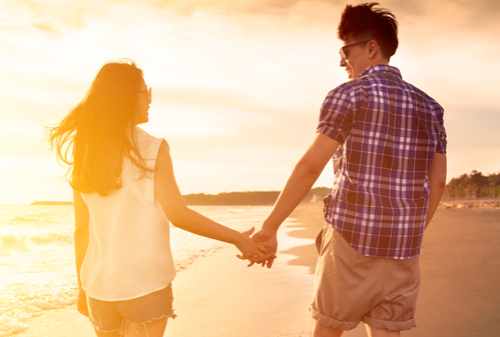 young couple enjoying a beach walk at sunset