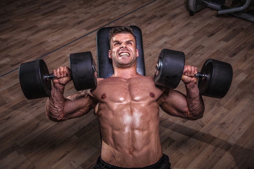 Man bench pressing heavy dumbbells