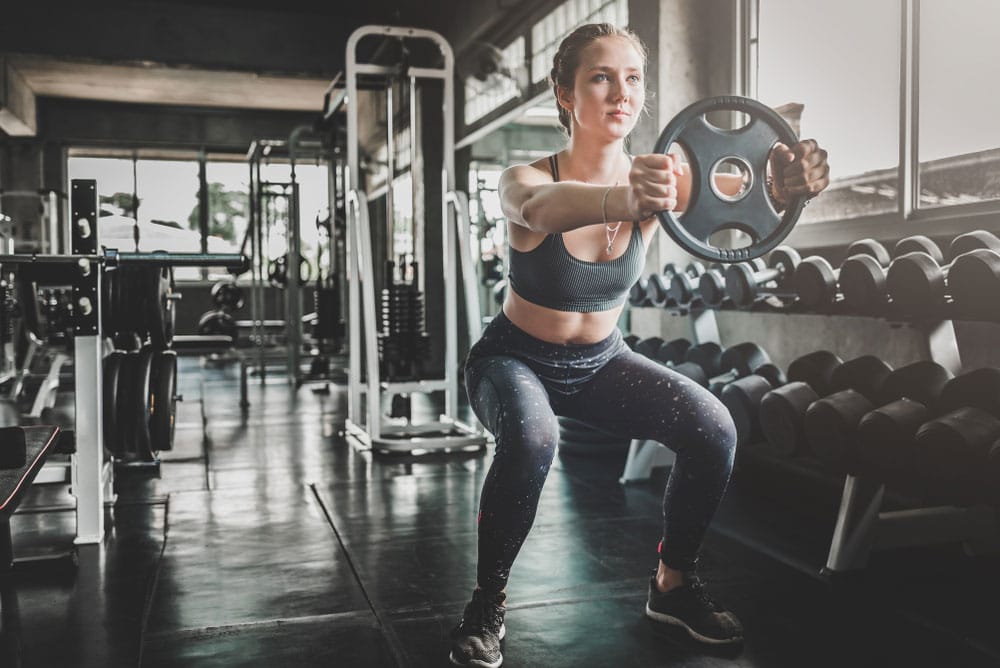 Woman doing plate press with a squat