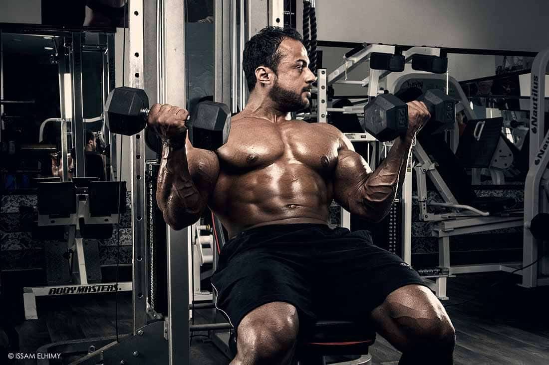 Young Man Working Out Biceps with Dumbbell for body beast program