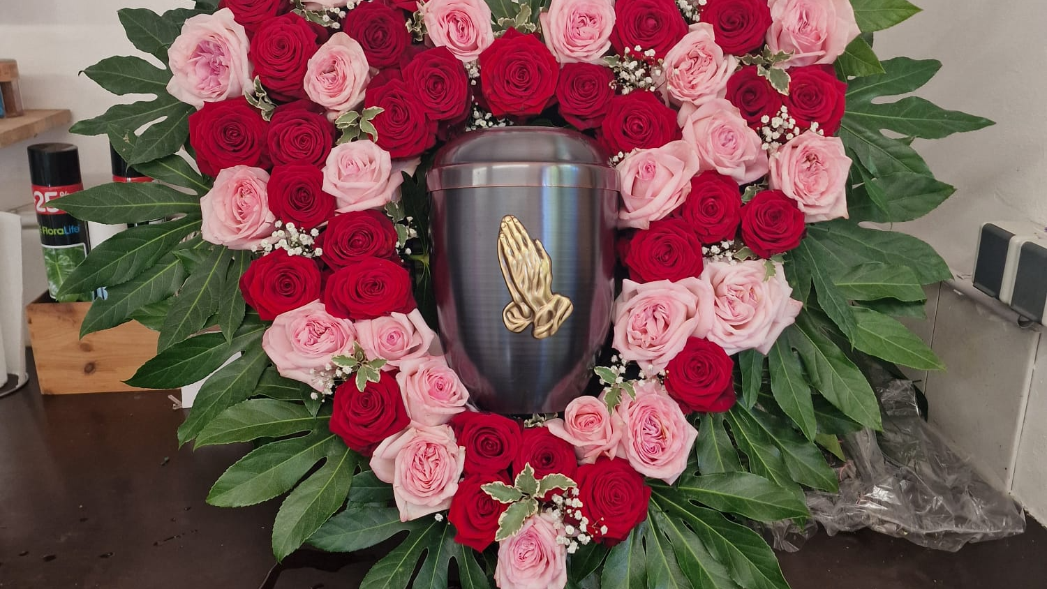 Eine Urne wird von einem Blumenarrangement geschmückt.