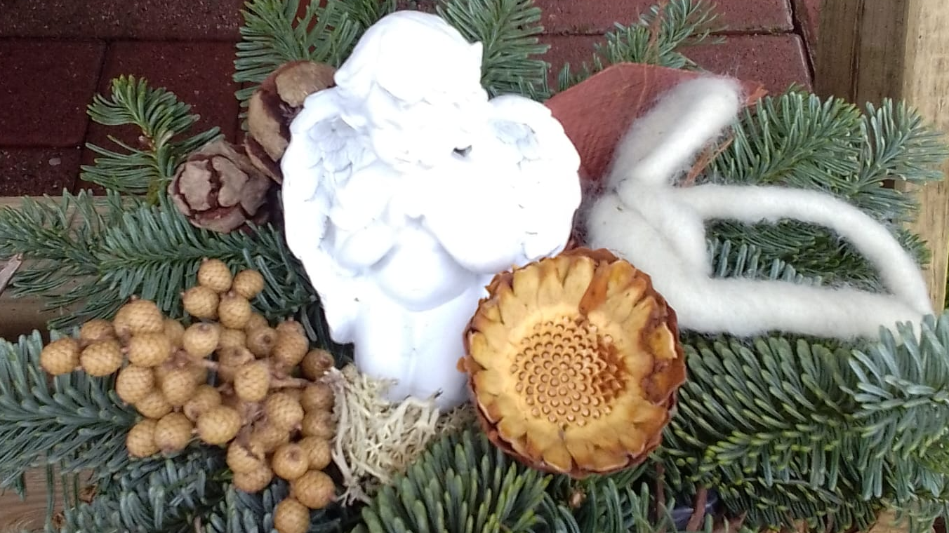In einer winterlichen Szene stehen rote, weiße und blaue Blumen in einer Vase auf einem Tisch.