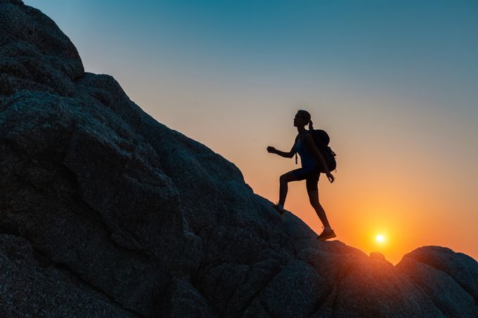 Lady walking on the rocks at sunset