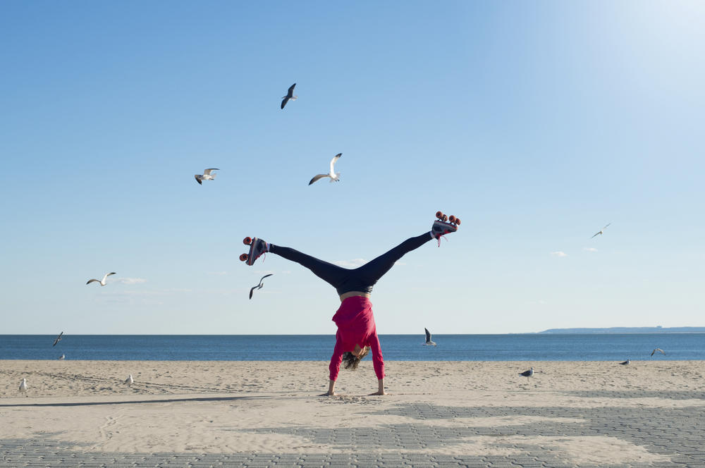 Yoga for beginners, everything you need to know-Woman cartwheeling on beach in roller skates