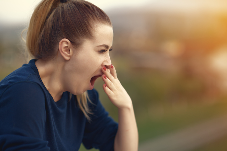 side view of young woman being tired and yawning,photo taken outdoors.sleepy and exhausted.