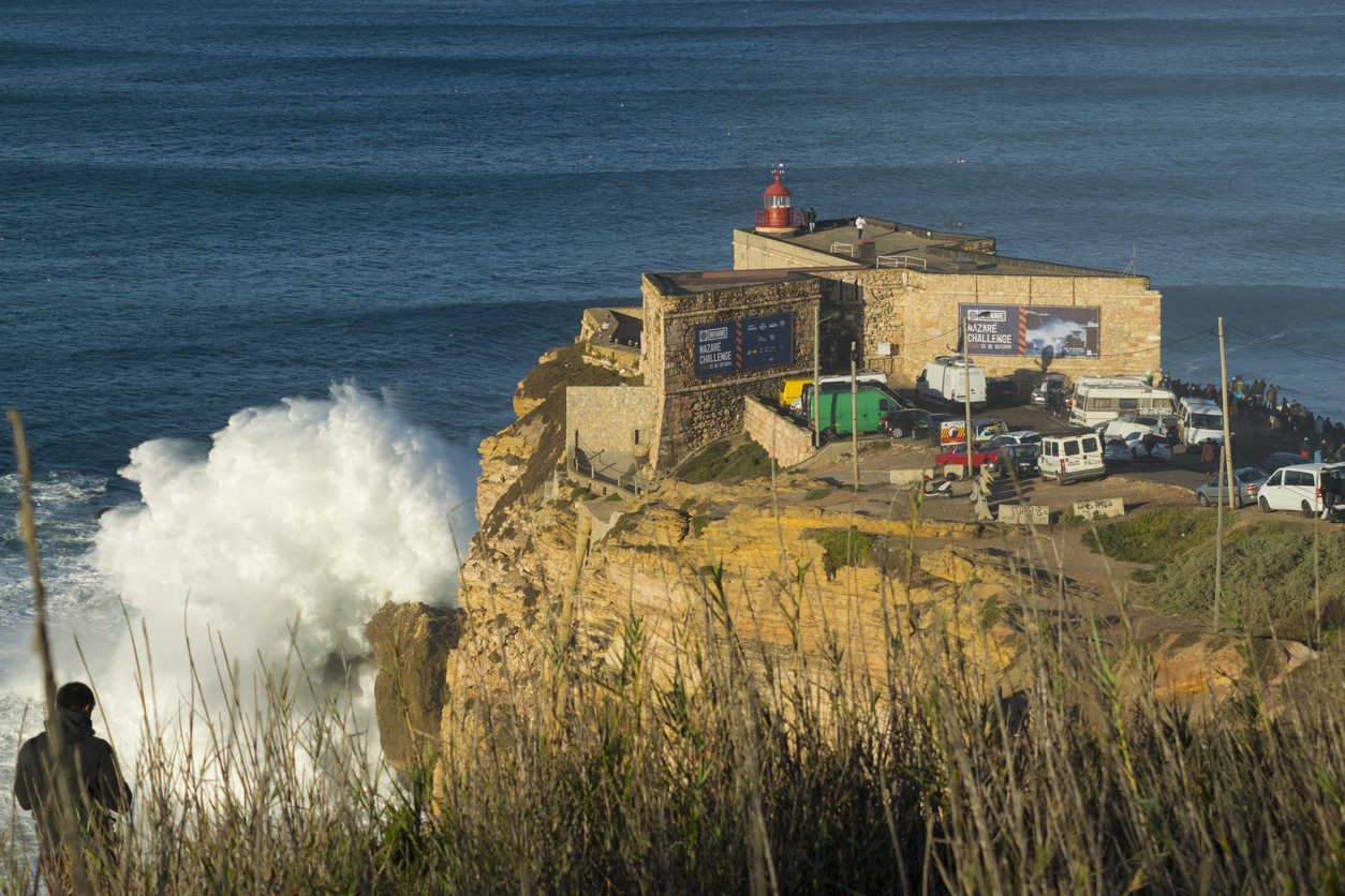 Waves crash against the famous lighthouse at Nazaré - PhotoL iStock