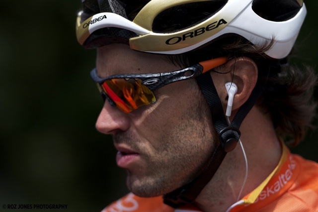 Cyclist, Sameul Sanchez, wearing a white and gold helmet, Oakley sunglasses, and an orange jersey