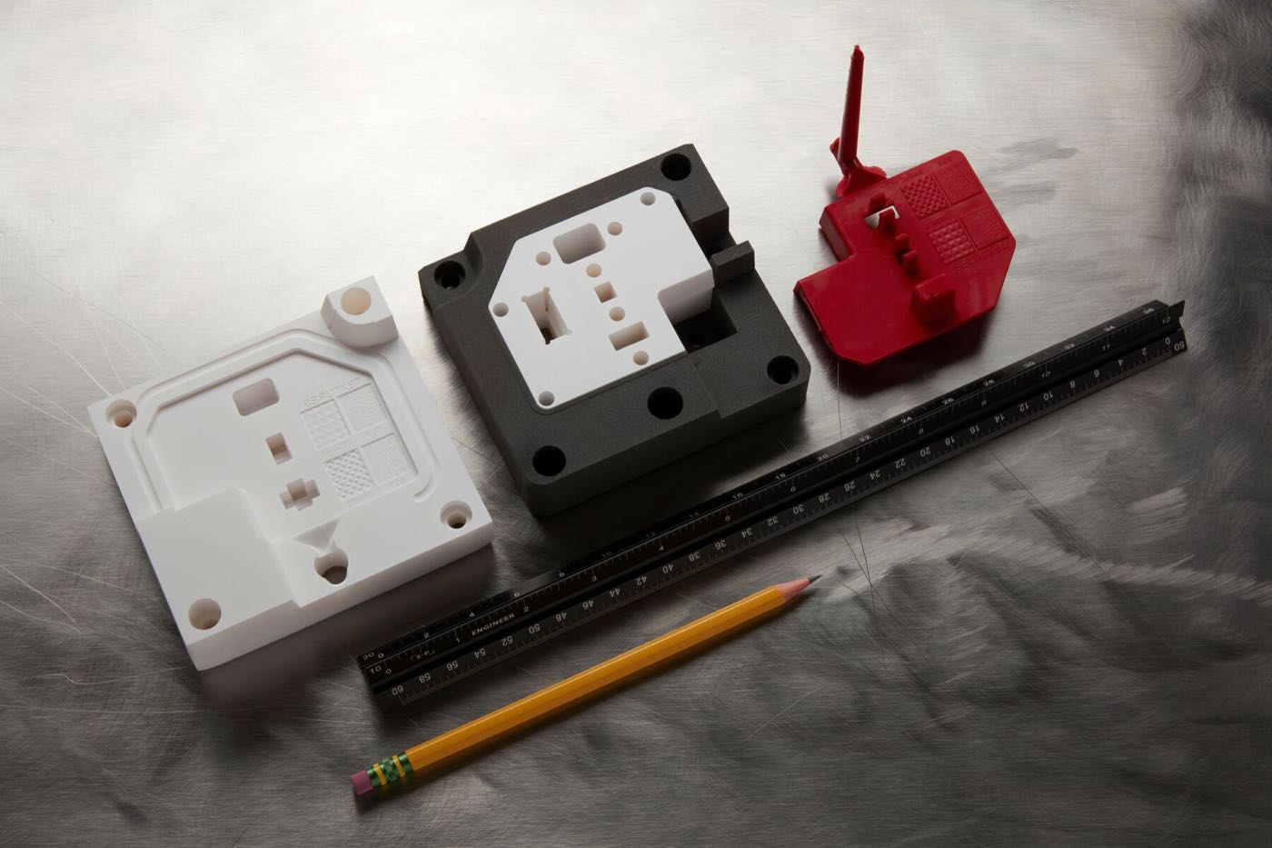 Formlabs Rigid 10K Resin injection molding insert next to the red thermoplastic part it molded