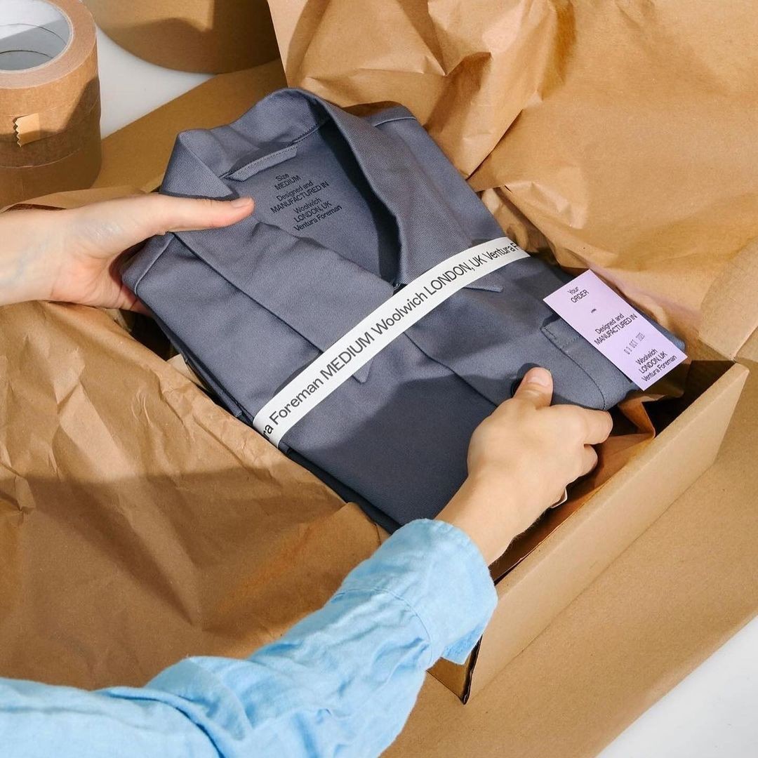 Hands packing a clothing order in kraft paper