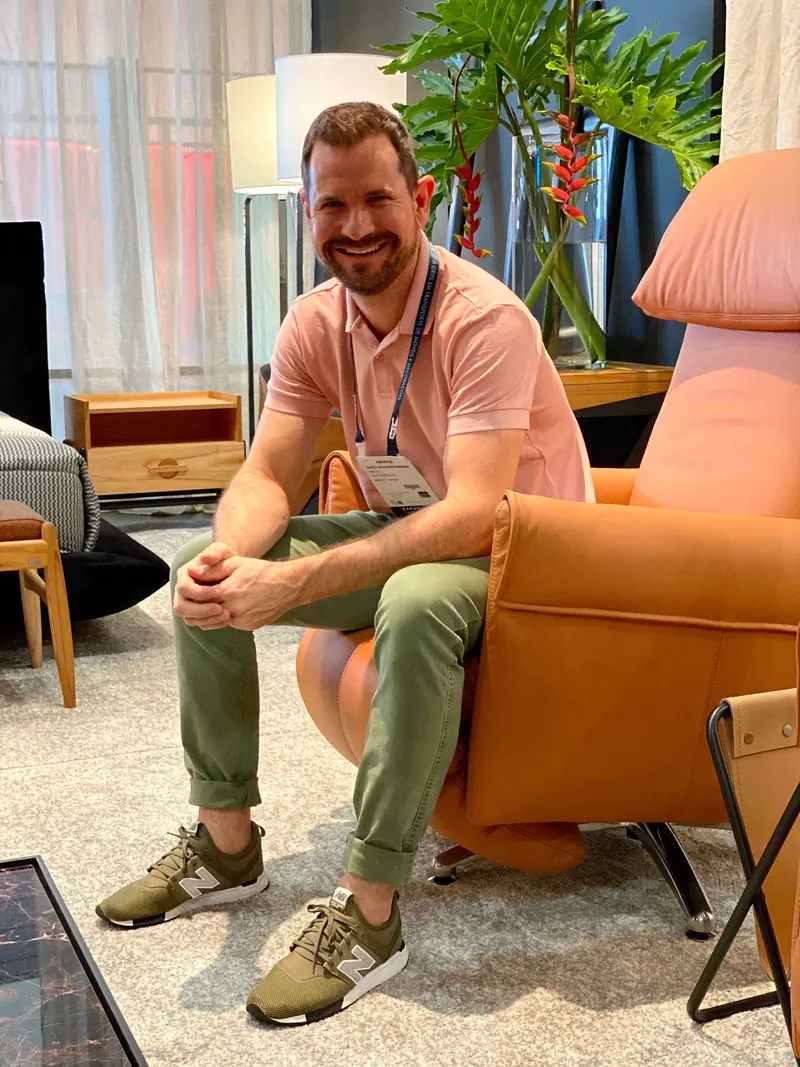 Na imagem, é possível visualizar um homem sentada em uma poltrona cor-de-rosa. 