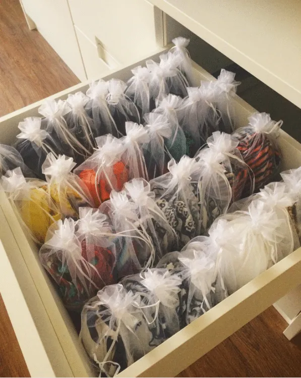 Dentro da gaveta é possível ver biquínis dobrados dentro do saquinho transparente de organza.