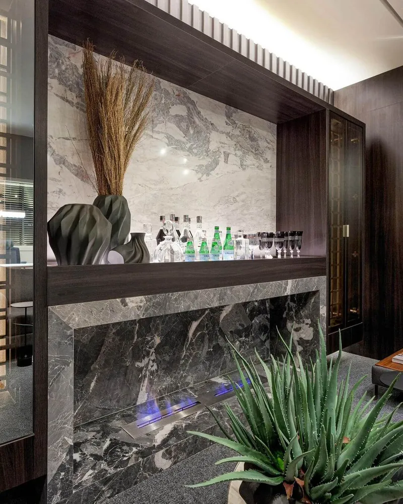 Lareira deixa o ambiente bonito e aconchegante no escritório Merenciano & Usso. Projeto de arquitetura de luxo da arquiteta Isabela Junqueira, de Maringá.