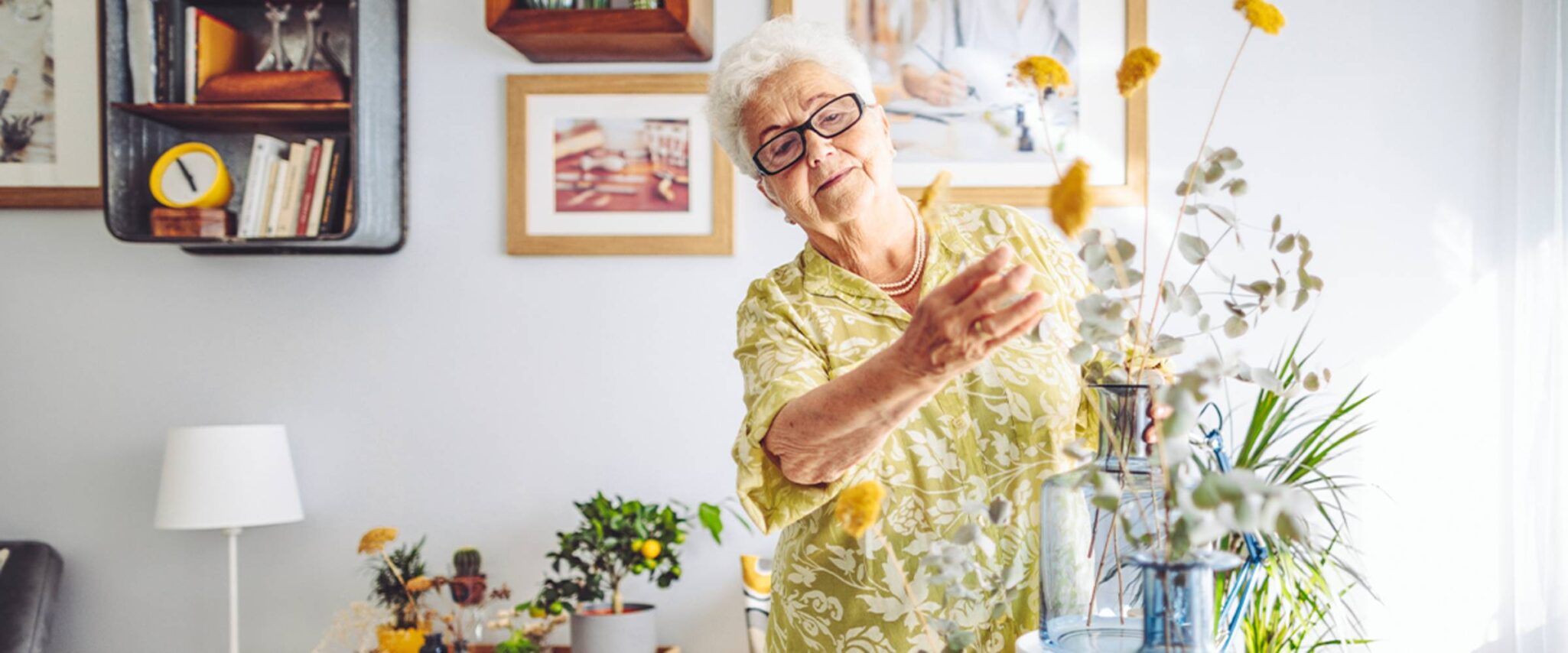An elderly woman arranges flowers in her senior apartment